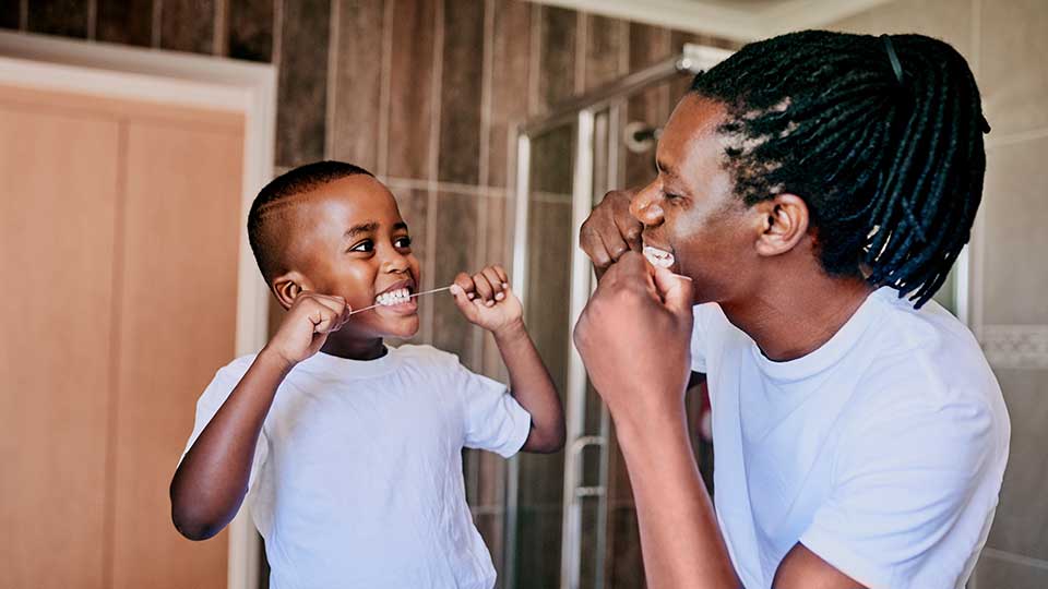 Father and son having fun while flossing their teeth