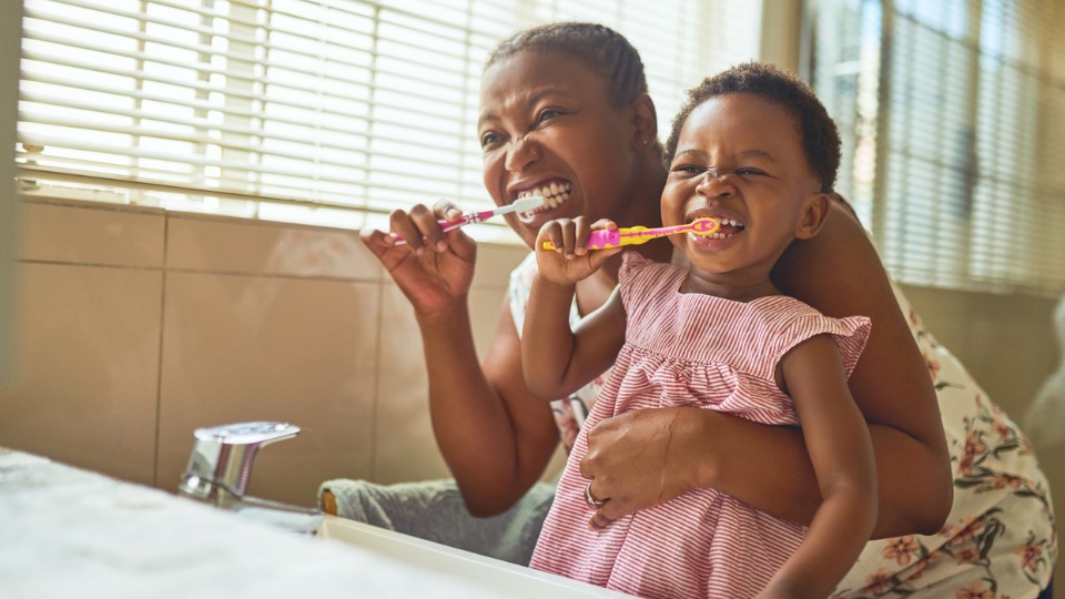 Mother and child brushing teeth together