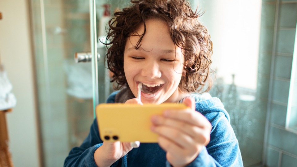 Little boy brushing teeth and using toothbrushing app